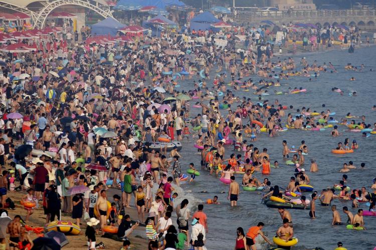 Besøgende på en strand i den kinesiske by Qingdao tidligere på måneden, da store dele af Kina led under en massiv hedebølge, 