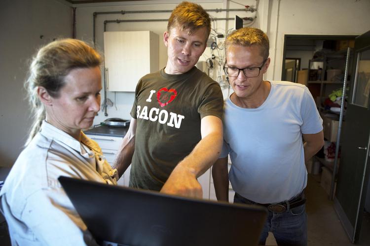 Kim Knudsen (med  bacon-t-shirt) og dyrlæge Hasse Poulsen studerer en graf for forbruget af  antibiotika, som Kims medarbejder Olga Nielsen har fundet frem. Klaus Holsting/POLFOTO