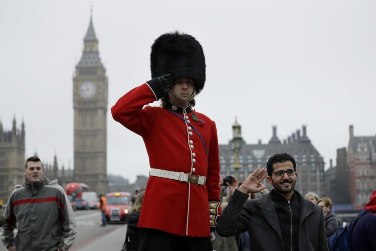 Alvorligt vagtskifte ved Westminster Bridge i London og fjollede turister. Foto: Matt Dunham/AP
 