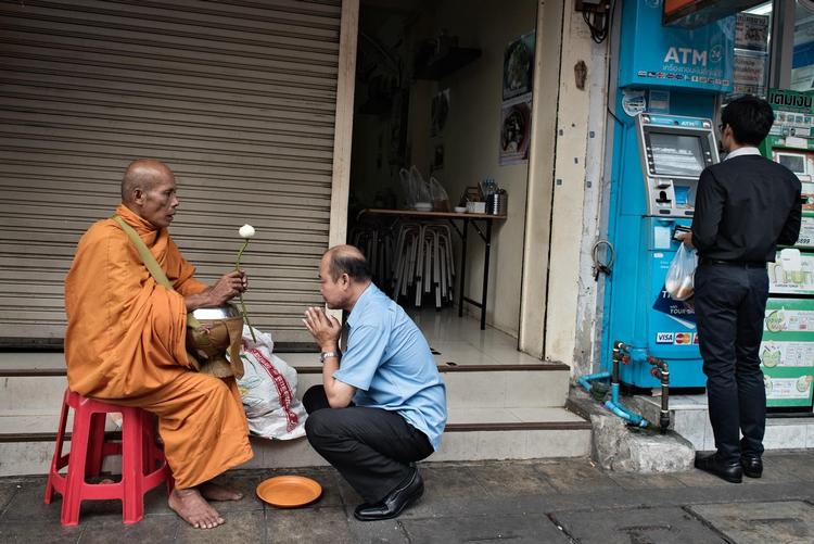Overalt i Thailand kan man om morgenen se munke, der samler mad ind. Her har en mand givet lidt til en munk i Bangkok, som til gengæld giver ham en form for velsignelse. Men stadig flere thailændere vender sig mere mod det moderne forbrugersamfund og ofrer ikke munkene stor opmærksomhed. (Arkivfoto) 