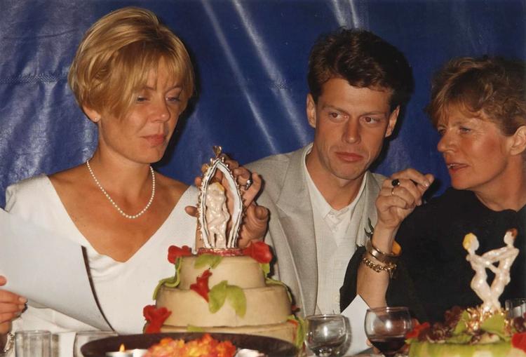 Det unge brudepar, Mette og Claus, betragter bryllupskagen, mens de lytter til brudens mor udlægge teksten.  Foto: Privatfoto