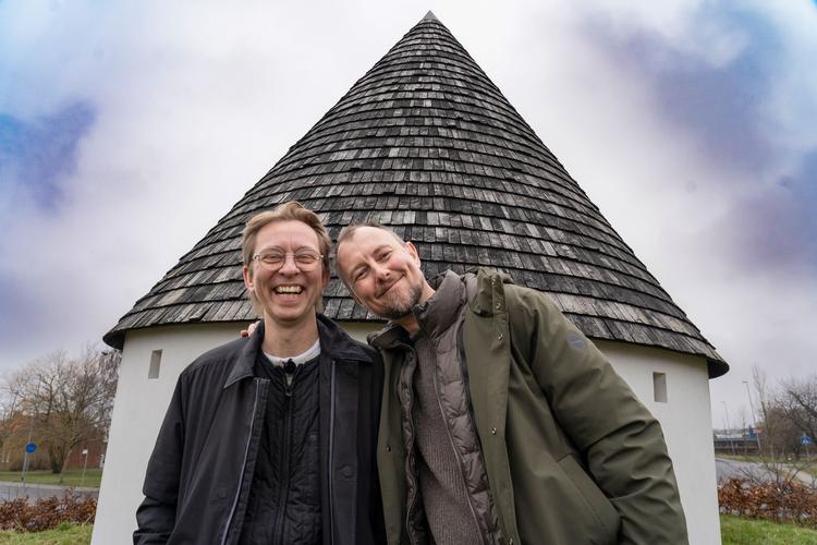 Brian Lykke og Kasper Nielsen foran den rundkirkeskulptur, der lokalt er blevet kaldt 'Smølfehuset'. Foto: 
Jesper Langballe/DR