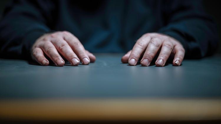 Hvem er han? Manden bag hænderne på bordfladen hos politiet. Han forbliver et mysterium i 'Børnelokkeren'. Foto: Still/DR
