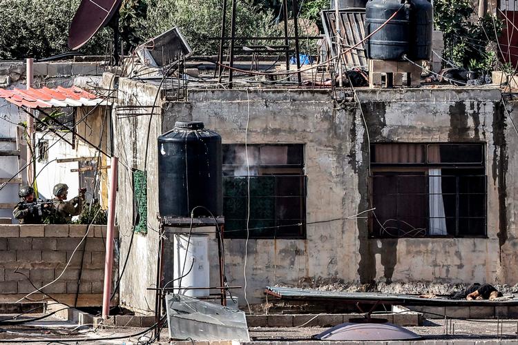 EIsraelske soldater nærmer sig en bygning i Qabatiya, hvor ligene af mænd, der angiveligt er blevet dræbt i kamp, befinder sig. Foto: Zain Jaafar/Ritzau Scanpix