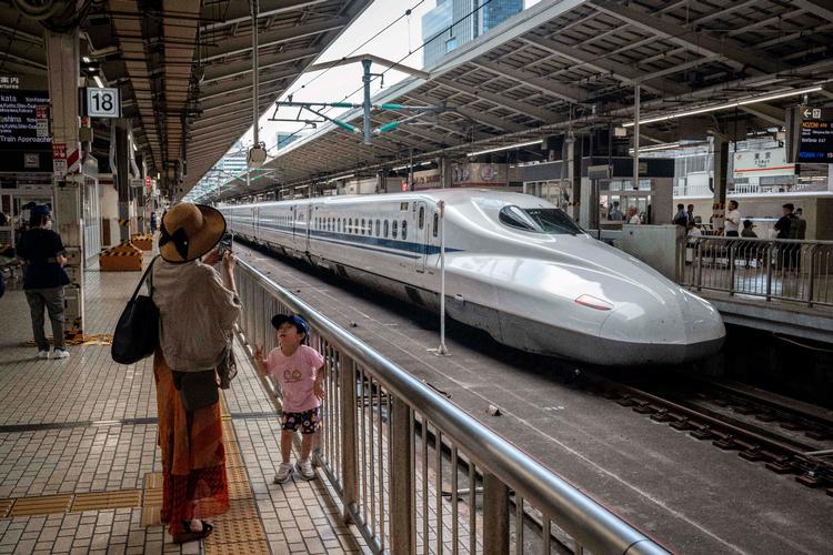 En mor tager et billede af sin søn foran et Shinkansen-tog i Tokyo. Højhastighedstoget fylder 60 år 1. oktober. Foto: Yuichi Yamazaki/Ritzau Scanpix