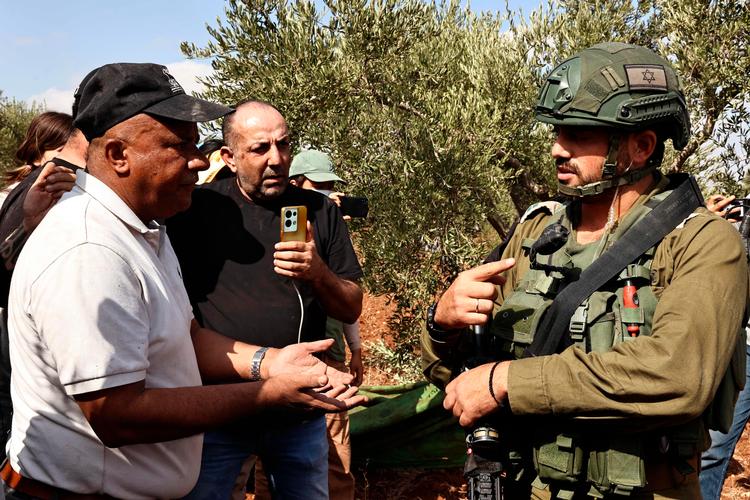 En israelsk soldat beordrer en palæstinensisk bonde på Vestbredden samt internationale frivillige til at forlade bondens olivenhøst. Foto: Zain Jaafar/Ritzau Scanpix