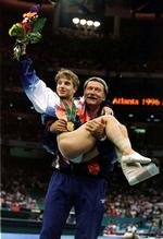 Béla Károlyi bærer Kerri Strug ned fra sejrspodiet, efter at den amerikanske gymnast har fået overrakt en guldmedalje ved OL i 1996. Strugs forhold til sin træner var ligesom flere andres kompliceret.  Arkivfoto:  Mike Blake
