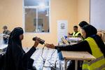 Naima Farhan ser ind i det kikkertlignende apparat og bliver derved skannet i øjnene og verificeret med irisgenkendelse. Processen tager få sekunder. Systemet genkender hendes iris, som tidligere er blevet oprettet, og hun må nu afgive sin stemme.,  Foto: Liv Latricia Habel