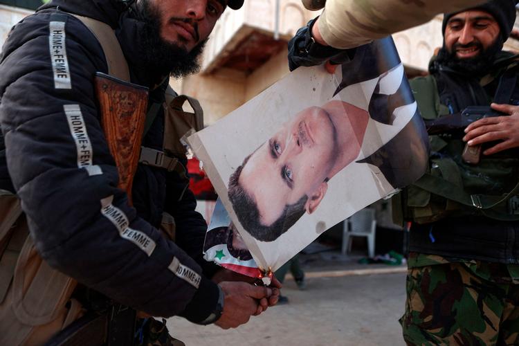 Oprørere sætter ild til en plakat af Bashar al-Assad i Aleppo-provinsen i sidste uge, hvor en blanding af jihadistiske og verdslige oprørere har fortrængt diktaturets militære styrer. Foto: Aaref Watad/Ritzau Scanpix