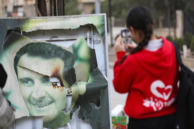 En syrisk kvinde foreviger den detroniserede præsident Bashar al-Assad i byen Qamishli. Foto: Orhan Qereman/Ritzau Scanpix