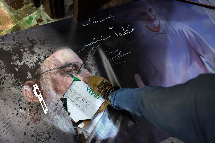 En syrer træder på en plakat af Hizbollah-lederen Hassan Nazrallah og den tidligere leder af Irans revolutionsgarde, Qassem Soleimani, foran den iranske ambassade i Syrien.
 Foto: Omar Haj Kadour/Ritzau Scanpix