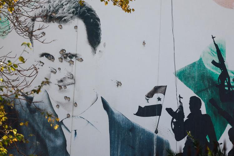 Et udendørs portræt af den syriske diktator Bashar al-Assad ses gennemhullet af kugler, efter at han blev jaget ud af landet.  Foto: Ammar Awad/Ritzau Scanpix
