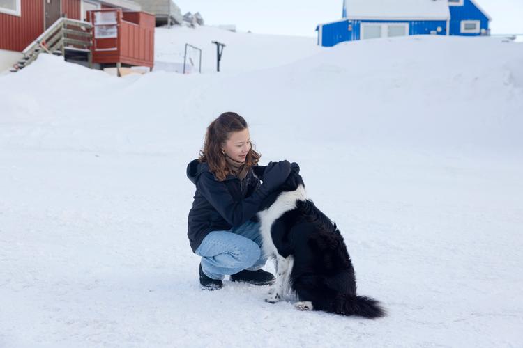 13-årige Aima med familiens hund, der hedder Nukik. Det betyder 'den stærke'. Familien taler både grønlandsk og dansk sammen, så nogle gange kommer der for eksempel et grønlandsk ord i det danske. Til Nukik taler de dog mest grønlandsk, fortæller Aima.  Foto: Cecilie Rolvung