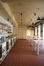 Gulvet har terrakottafliser, og loftet er i fyrretræsfiner. Køkkenelementerne er i stål og birk, som giver en usædvanlig grad af raffinement og hygge til et skolekøkken.  Foto: Claus Pryds