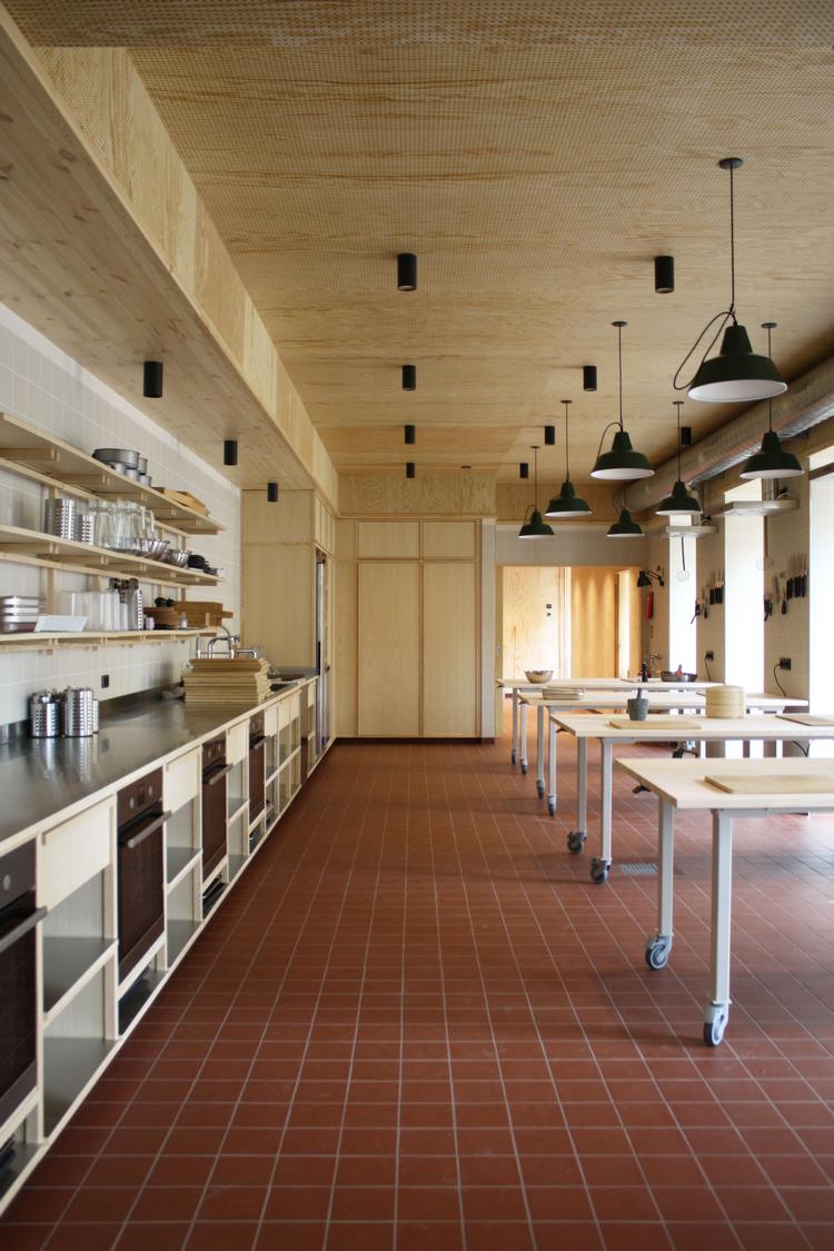 Gulvet har terrakottafliser, og loftet er i fyrretræsfiner. Køkkenelementerne er i stål og birk, som giver en usædvanlig grad af raffinement og hygge til et skolekøkken.  Foto: Claus Pryds