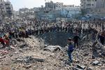 Palæstinensere samles om et krater skabt af et israelsk luftangreb i Gaza By søndag. Foto: Omar Al-qattaa/Ritzau Scanpix