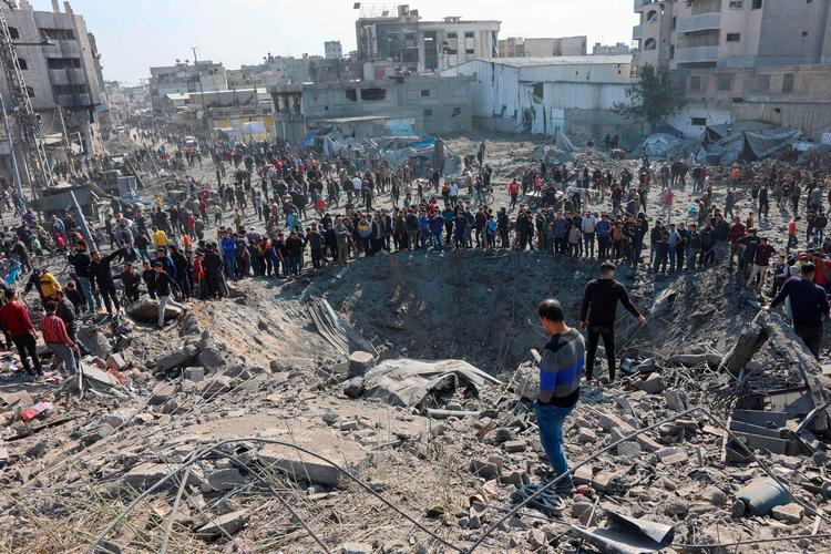 Palæstinensere samles om et krater skabt af et israelsk luftangreb i Gaza By søndag. Foto: Omar Al-qattaa/Ritzau Scanpix