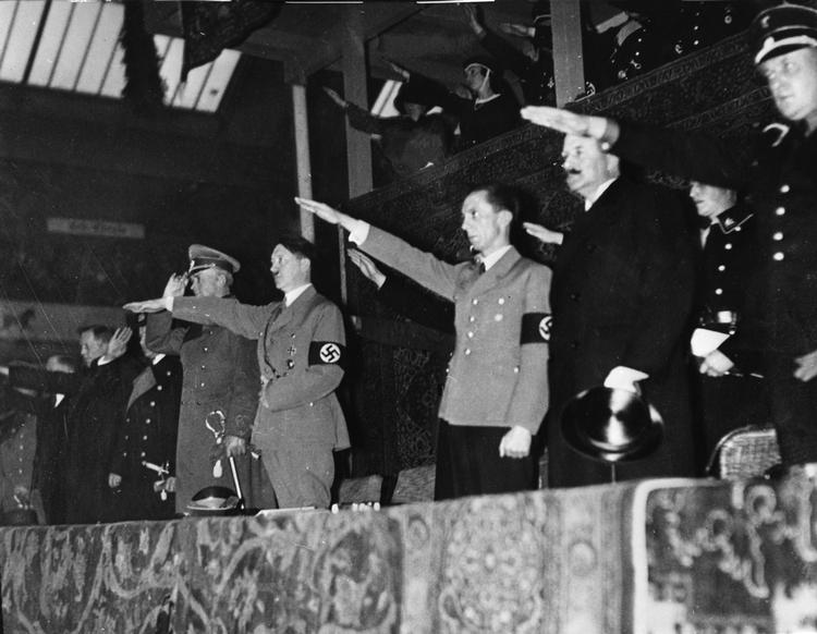 Hitler var blevet valgt demokratisk, da han 30. januar 1933 blev kansler. På under 100 dage fik han udstedt dekreter, der gjorde tyskerne bange for, hvad de sagde og skrev. Angsten for overvågning slog rod i deres underbevidsthed. 
Her står han i Berlin 1935. På billedet ses også Joseph Goebbels (nummer tre fra højre), der var Det Tredje Riges propagandaminister fra 1933 til 1945.  Foto: /Ritzau Scanpix