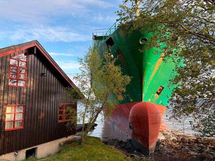 Det ligner et AI-genereret billede, men den er god nok. Et containerskib stødte på grund klos op ad en bolig ud til Trondheimsfjorden i Norge. Foto: Ntb/Ritzau Scanpix