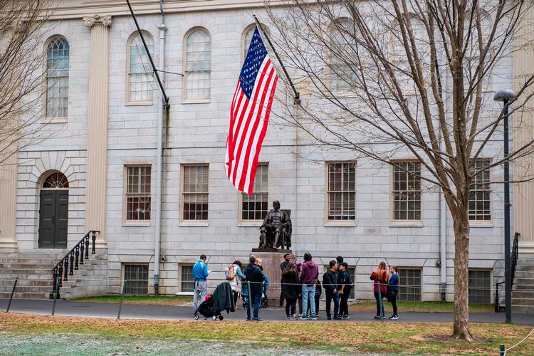 Folk samles omkring statuen af Harvard Universitys stifter John Harvard på universitetets campus i Cambridge, Massachusetts, mens kampen bølger mellem Trump-regeringen og universitetet. Foto: Joseph Prezioso/Ritzau Scanpix