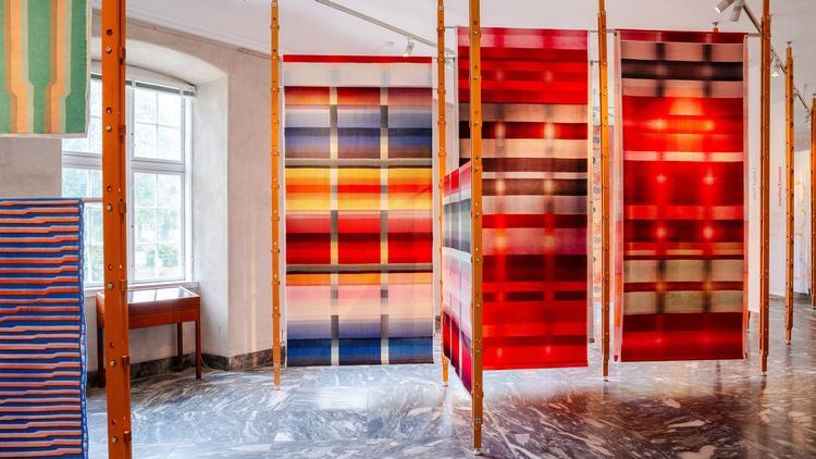 Designduoen Mentze Ottenstein har hængt alle de trykte tekstiler op på store træstativer, der minder om tørrestativer. På den måde kan man komme helt tæt på stofferne, som alle er trykt i hånden.  Foto: Designmuseum Danmark