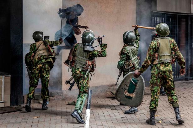 En demonstrant hopper i sikkerhed ud fra en smal allé, mens betjente slår hende med pisk og køller i Nairobi.  Foto: Luis Tato/Ritzau Scanpix