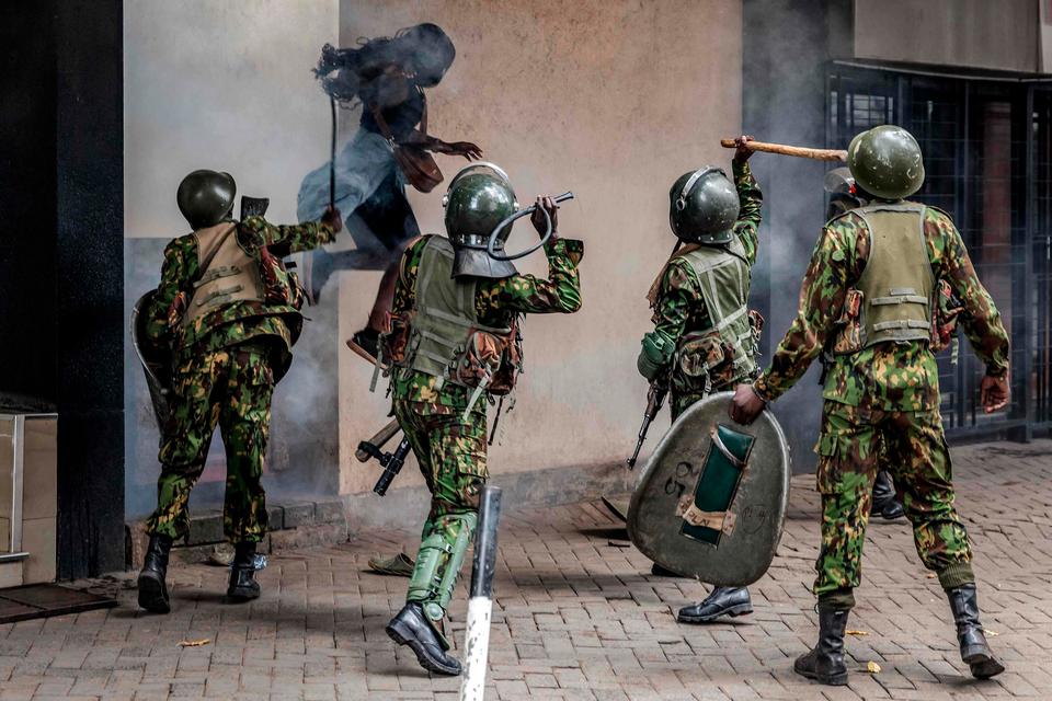 En demonstrant hopper i sikkerhed ud fra en smal allé, mens betjente slår hende med pisk og køller i Nairobi.  Foto: Luis Tato/Ritzau Scanpix