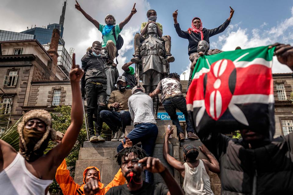 Demonstranter klatrer på en statue til minde om de østafrikanske soldater under 1. verdenskrig.  Foto: Luis Tato/Ritzau Scanpix