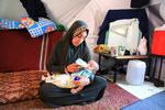 Den palæstinensiske kvinde Fatmeh Jundieh sidder i sit telt i Gaza City med en af sine to måneder gamle tvillinger, som hun kæmper med at finde mælkepulver og bleer til.   Foto: Ebrahim Hajjaj/Ritzau Scanpix