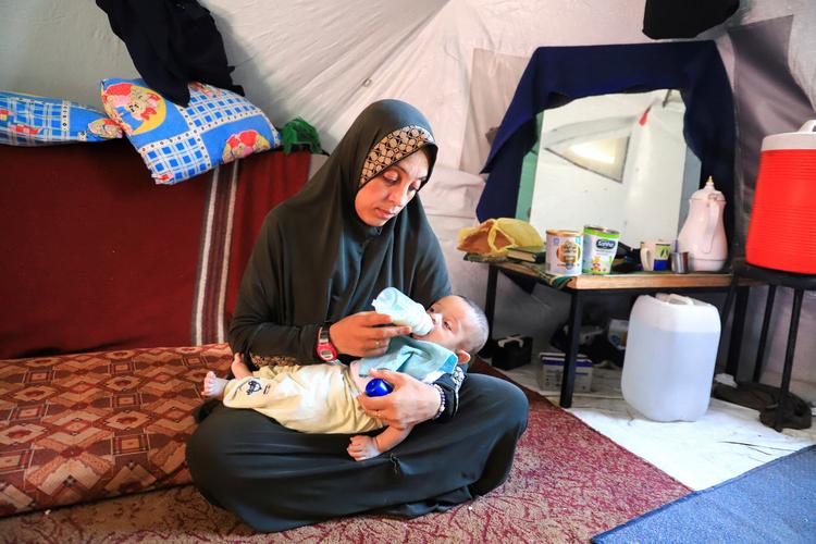 Den palæstinensiske kvinde Fatmeh Jundieh sidder i sit telt i Gaza City med en af sine to måneder gamle tvillinger, som hun kæmper med at finde mælkepulver og bleer til.   Foto: Ebrahim Hajjaj/Ritzau Scanpix