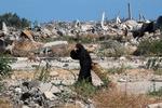 Gaza er sønderbombet.  Her drikker en fordrevet kvinde vand, mens hun slæber et stykke træ i det centrale Gaza onsdag.   Foto: Eyad Baba/Ritzau Scanpix