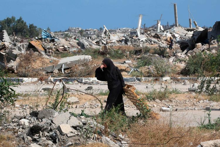 Gaza er sønderbombet.  Her drikker en fordrevet kvinde vand, mens hun slæber et stykke træ i det centrale Gaza onsdag.   Foto: Eyad Baba/Ritzau Scanpix