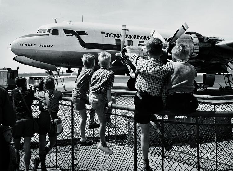 De færreste havde råd til at komme ud at flyve i 1950'erne, men man kunne da altid kigge på fly og måske vinke til passagererne om bord. Her der det en af SAS' DC-4-maskiner, der bliver beundret.   Foto: CPH / Historisk Arkiv