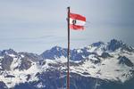 Den østrigske statsflag med rigsvåben blafrer let i den lune forårsvind. I Montafon begynder skisæsonen første weekend i december – eller så snart der er sne. De sidste skiområder lukker typisk ned i slutningen af april. Foto: Alexander Vissing