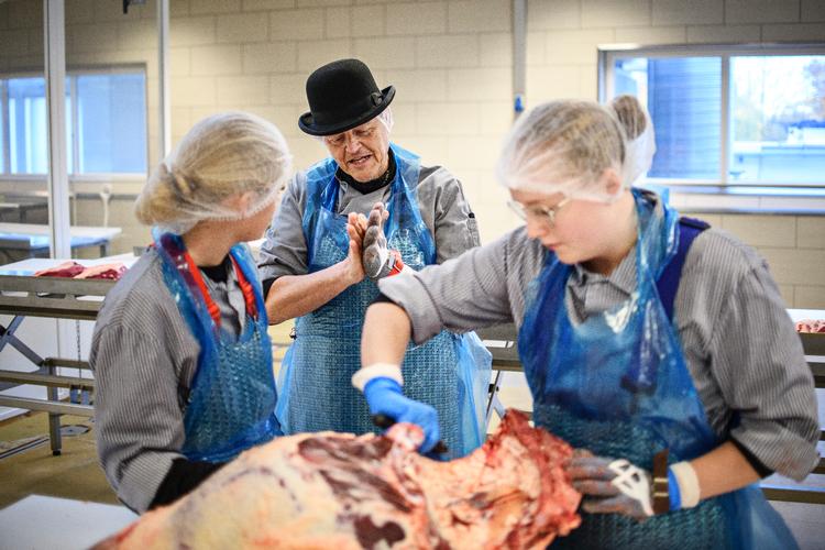 Gourmetslagter Michael Busk »lever og ånder« for sit fag, siger hans elever fra Danmarks Slagteriskole, ZBC, i Roskilde. Her guider han to af dem i at udskære dagens oksepistol. Foto: Janus Engel/Janus Engel