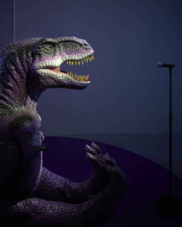 En dinosaur synger karaoke fra fortiden om længsel og kærlighed i Monira al Qadiris værk fra 2022, 'Seismiske sange'. Den olie, vi borer op af undergrunden, er lavet af fortidens biologiske materiale. En dinosaur for eksempel.  Pr-foto: Anders Sune Berg 