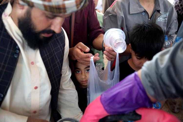 En afghansk dreng, der er blevet deporteret fra Iran for nylig, venter på at få udleveret noget at drikke i Herat-provinsen.  Foto: Sayed Hasib/Ritzau Scanpix