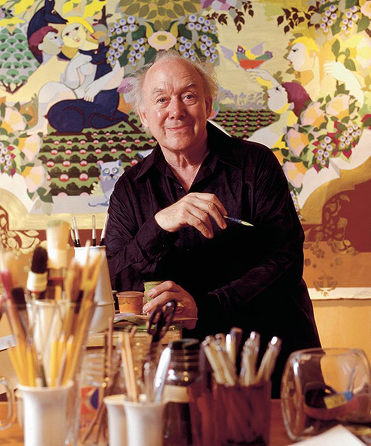 Bjørn Wiinblad i sit atelier foran et karakteristisk værk med ornamentik, mønstre og stiliserede mennesker og dyr.  Foto: Bjørn Wiinblads Fond