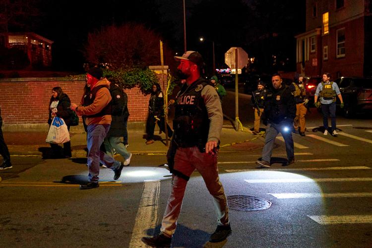 Politibetjente eskorterer studerende væk fra den bygning på Brown Universitys campus, hvor skyderiet, der dræbte to studerende, fandt sted lørdag eftermiddag lokal tid. Foto: Bing Guan/Ritzau Scanpix