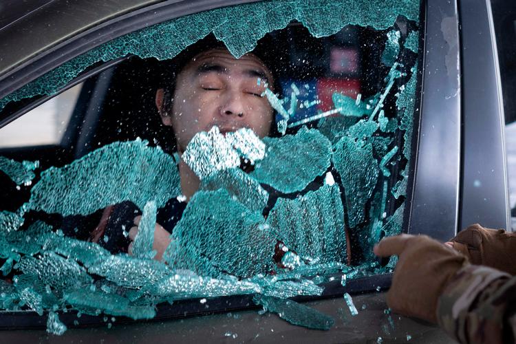 En betjent smadrer bilruden og trækker end mand ud af bilen, da han ikke har kunnet fremvise tilfredsstilende dokumentation for sit statsborgerskab. Episoden foregik i St. Paul i Minnesota i søndags.  Foto: Scott Olson/Ritzau Scanpix