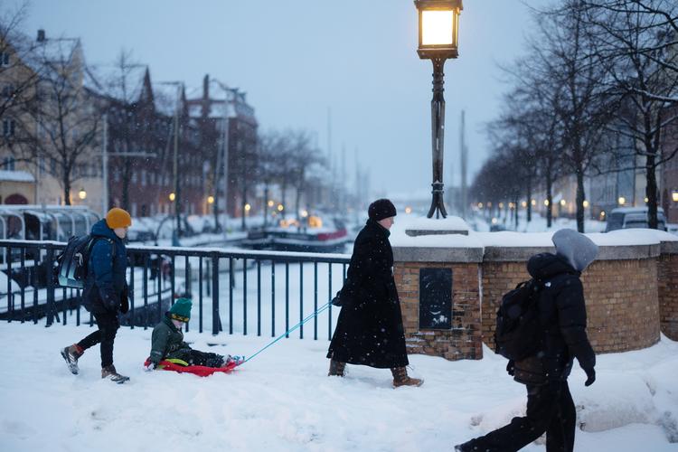 Der er faldet store mængder sne i København, og byen er dækket af et tykt lag sne. En kvinde trækker en dreng på en bobslæde gennem sneen på fortovet. Foto: Thomas Borberg