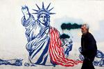 Iraner passerer et vægmaleri af den amerikanske frihedsgudinde med en brækket fakkelbærende arm, malet på ydervæggene af den tidligere amerikanske ambassade i Teheran. Foto: -/Ritzau Scanpix