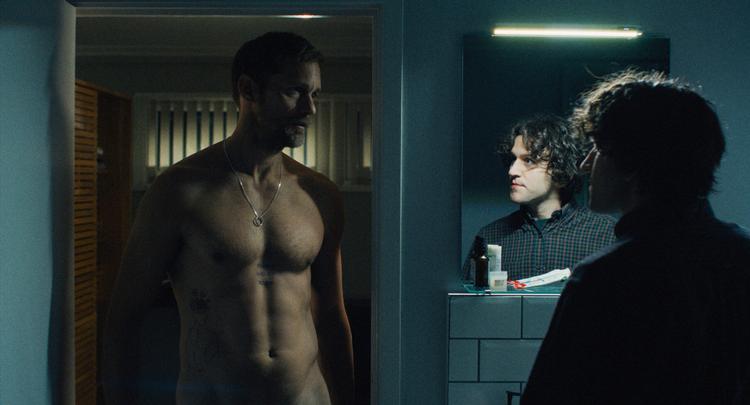 Colin (Harry Melling, th.) forelsker sig i bikeren Ray (Alexander Skarsgård), men hvordan får man dagligdagen til at fungere midt i et rollespil, hvor den ene er dominerende og den anden uden kontrol? Hvad gør man efter brydning, analsex og Tiffanys 'I Think We're Alone Now', når sengetidsrutinerne skal på plads? Foto: Reel Pictures