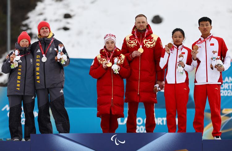 Linn Kazmaier og hendes guide Florian Baumann (tv.) holdt afstand til de russiske guldvindere Anastasiia Bagiian og Sergei Siniakin ved medaljeceremonien efter sprintkonkurrencen i langrend. Til højre de kinesiske bronzevindere Jihong Cong og Jiaxuan. Foto: Sarah Meyssonnier/Ritzau Scanpix