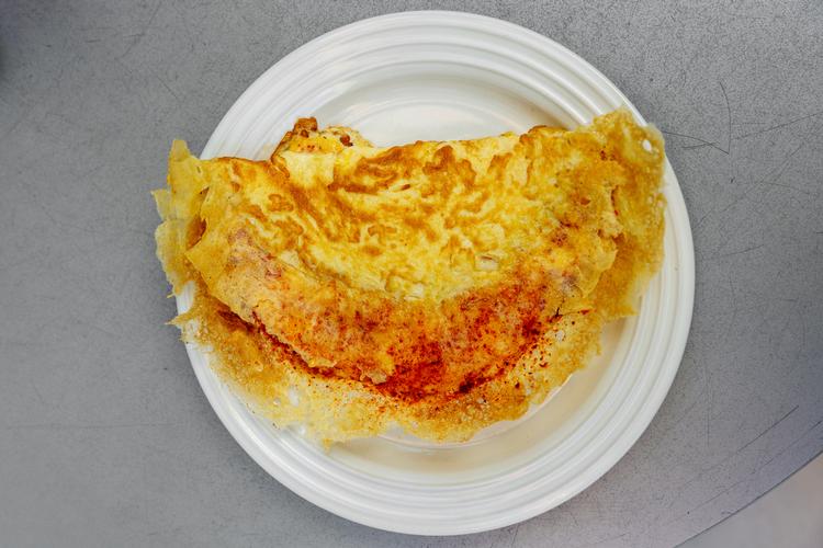 Ved to små induktionsplader bag disken laver kokken Mati Pichci de bedste omeletter, der kan opdrives i Danmark. Foto: Miriam Dalsgaard