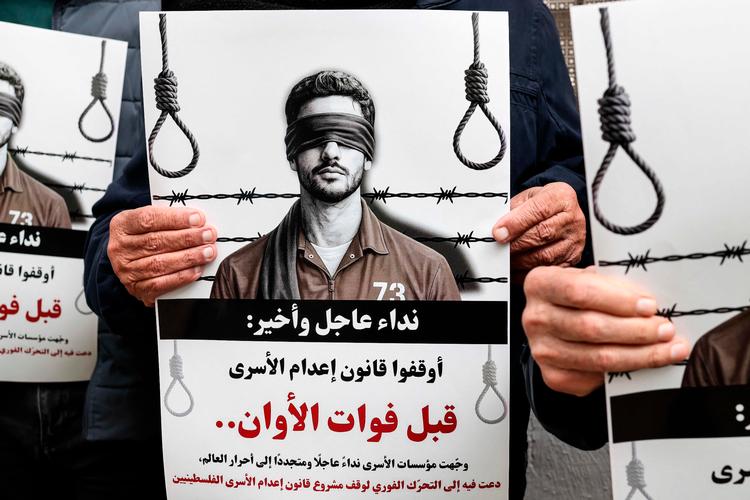 Demonstranter holdt tirsdag protestskilte mod den nye lov om dødsstraf uden for Røde Kors' kontorer i Ramallah på den israelsk-besatte Vestbred. Foto: Zain Jaafar/Ritzau Scanpix