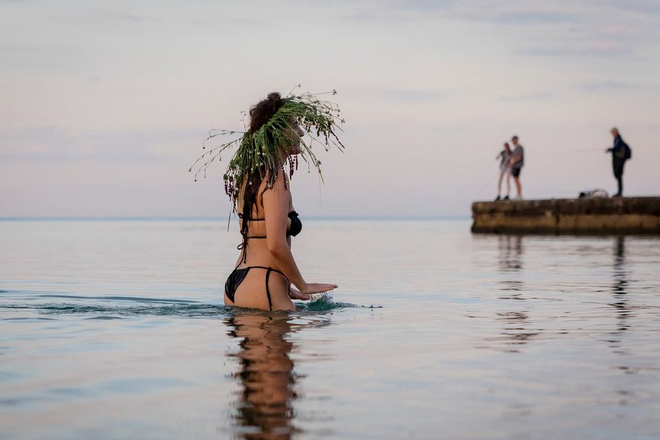 En kvinde med blomsterkrans på hovedet er gået ud i vandet ved sortehavsbyen Odesa under midsommernatten Ivan Kupala.  Foto: Oleksandr Gimanov/Ritzau Scanpix
