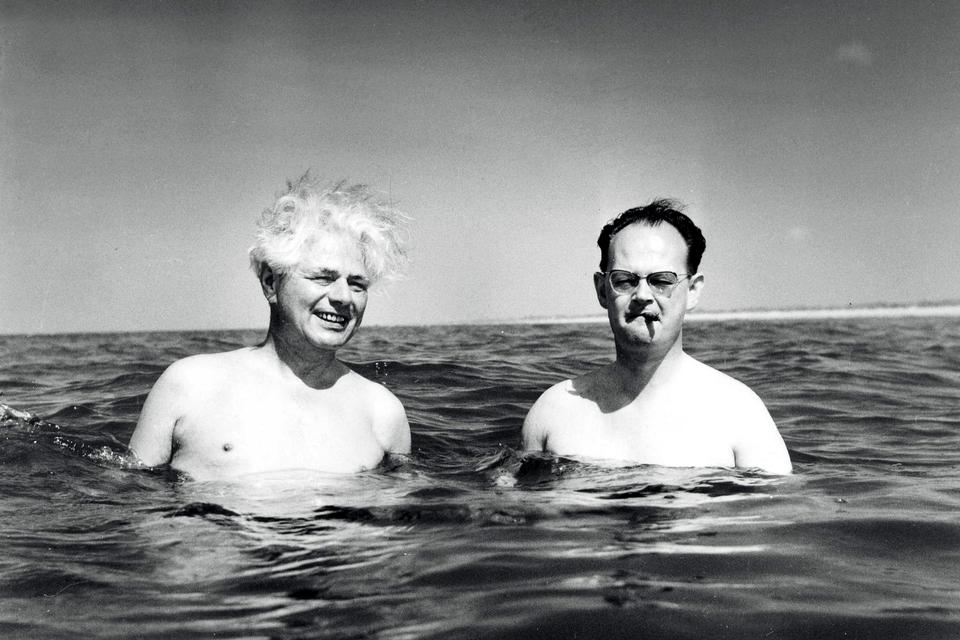 Året er 1955: Landet regeres fra Fanø. H.C. Hansen er i Paris, så finansminister Viggo Kampmann fungerer som stedfortræder og nyder badelivets glæder sammen med  undervisningsminister Julius Bomholt. Fotografen tilstår senere, at de to politikere ikke var på så dybt vand. Han fik dem til at gå på knæ.   Arkivfoto:  Tage Christensen