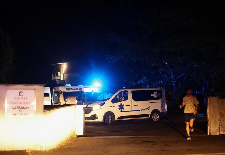 En ambulance forlader et plejehjem i Saint-Aubin-de-Médoc, mens en skovbrand raser i nærheden. Branden udvikler sig på baggrund af forværrede tørkeforhold efter en hedebølge og udbredt vandmangel i store dele af Frankrig. Billedet er taget den 25. juli 2026. Foto: Manon Cruz/Ritzau Scanpix