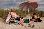 Solhat og solcreme. Morten Arneke er tømrer og har lært at passe på solen i sit job. På stranden i Ishøj er hans hustru ved at brune rygstykkerne inden på lørdag, hvor hun skal til stor fest i fin kjole med bar ryg.  Foto: Jacob Ehrbahn